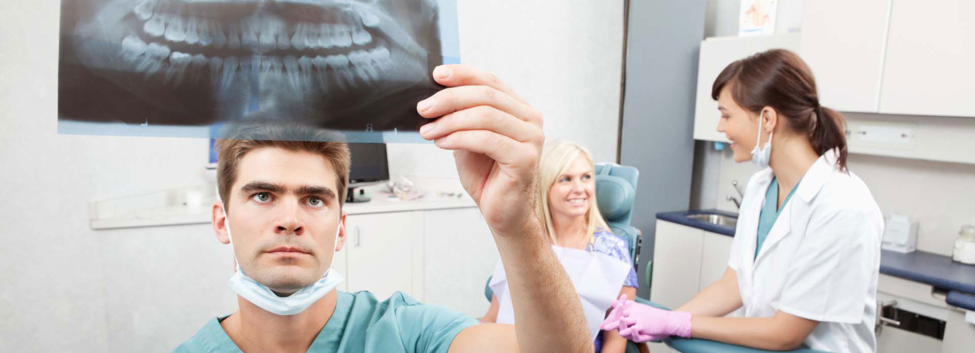 A dentist holding a tooth x-ray below a light source