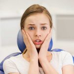 Scared and terrified patient girl at dental clinic